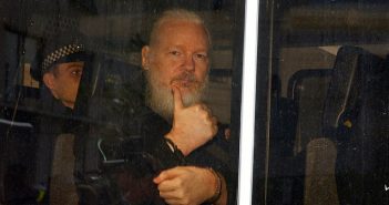 Julian Assange in handcuffs thumbs up